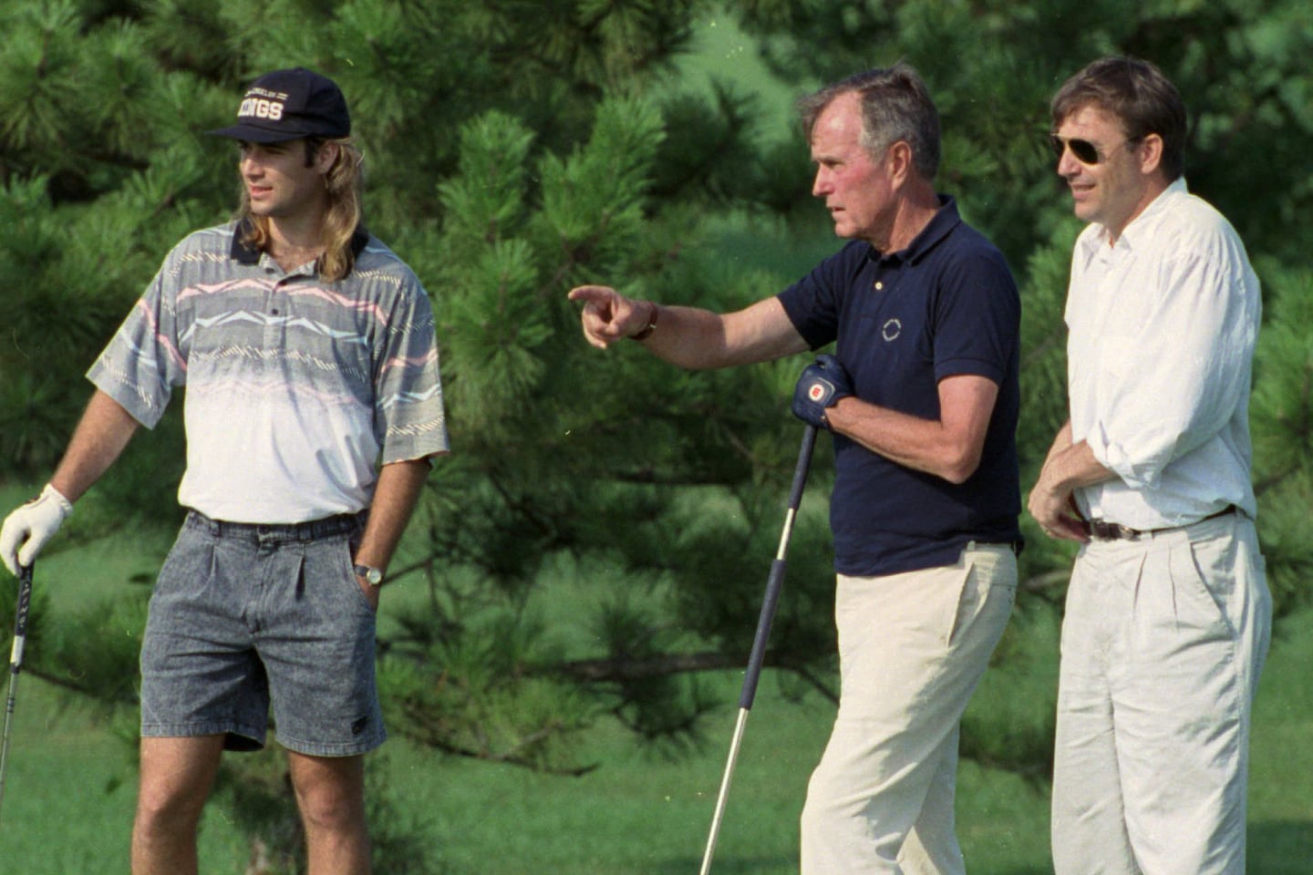Then-President George H.W. Bush talks with tennis star Andre Agassi, left, and actor Kevin Costner, right, while playing the 18th hole at Andrews Air Force Base, Md., July 28, 1991. 