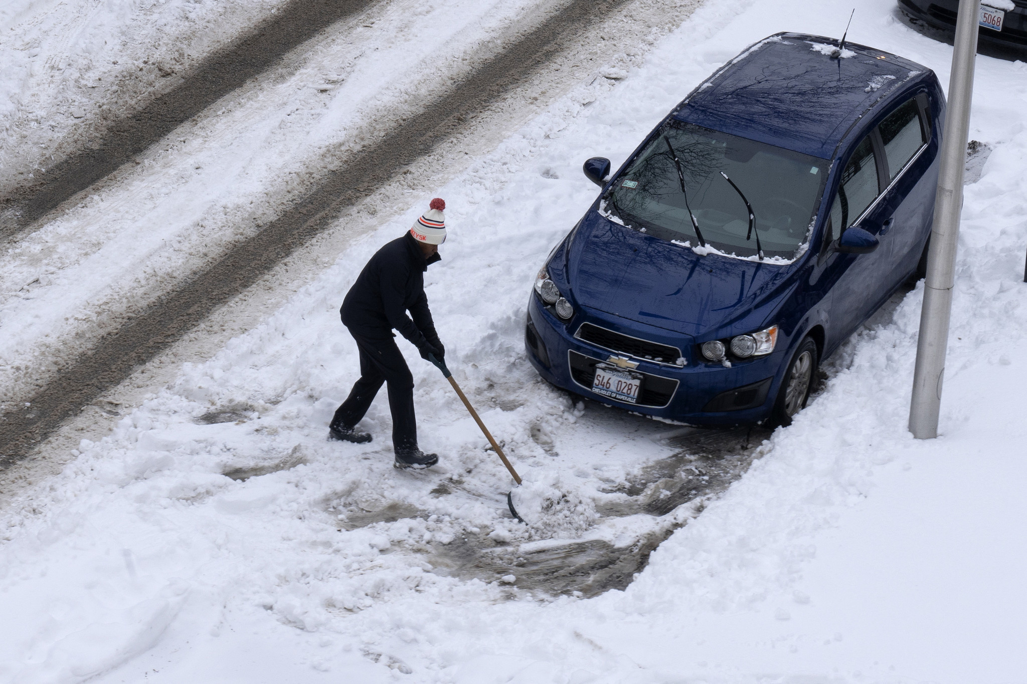A man shovels snow off the sidewalk after an overnight...