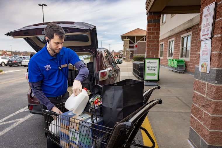 Wegmans employee Erik Van Slaars loads an online order into a customer's vehicle in the curbside pickup area outside the Mount Laurel store.