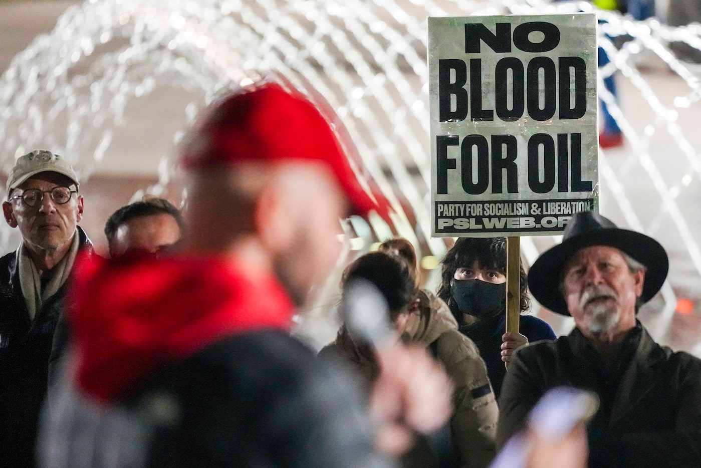 A demonstrator holds a sign reading "No Blood For Oil" at Civic Gardens during a protest...