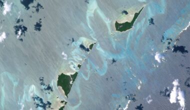 An astronaut photo of two islands in the Bahamas surrounded by twisting ribbons of shining blue sand banks