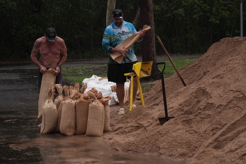 Men filling sandbags in rain. 