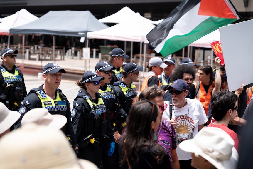 Several police move a crowd back in a public space
