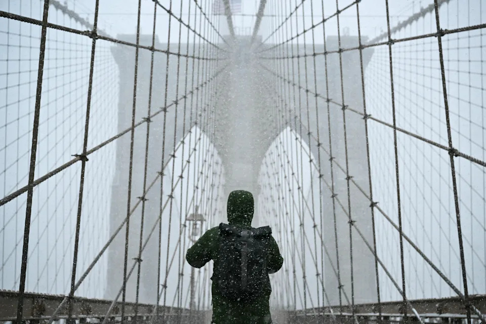 A man walks along the Brooklyn Bridge as snow falls in New York City on Jan. 25, 2026.