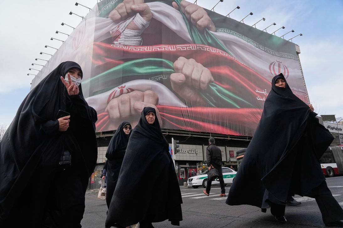 Women cross a street under a huge propaganda poster in Tehran. (AP Photo/Vahid Salemi)