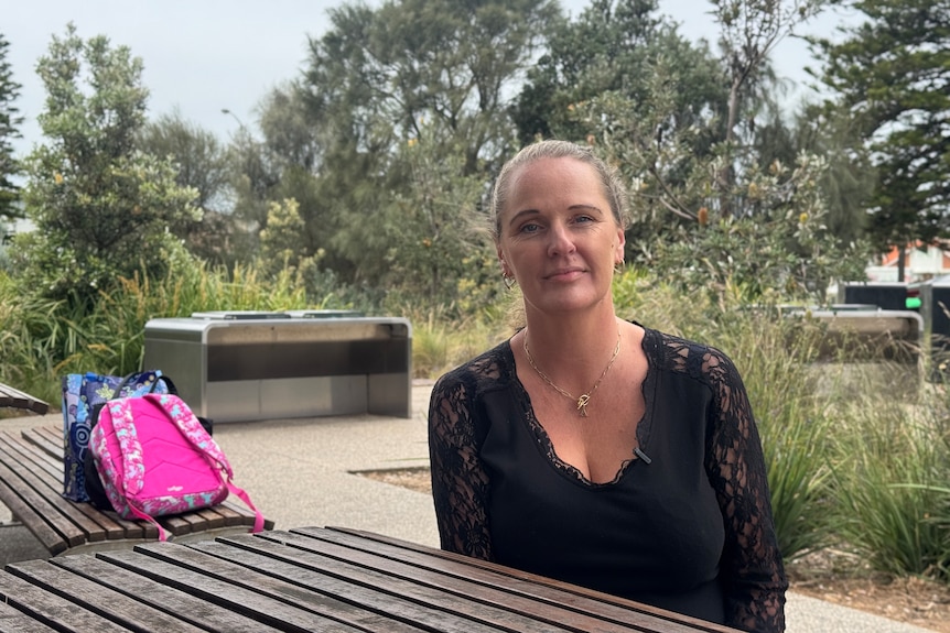 Amanda looks at the camera with a serious expression on her face while sitting on a park bench.