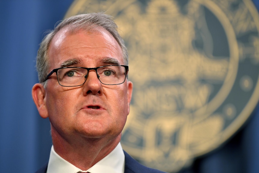 Michael Daley in a suit at a press conference.