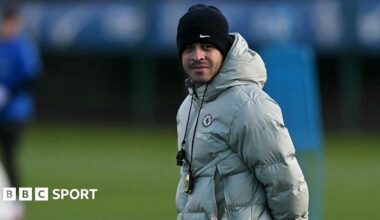 Liam Rosenior, wearing a silver puffer jacket and a black woolly hat and with a whistle and stopwatch around his neck, watches a Chelsea training session