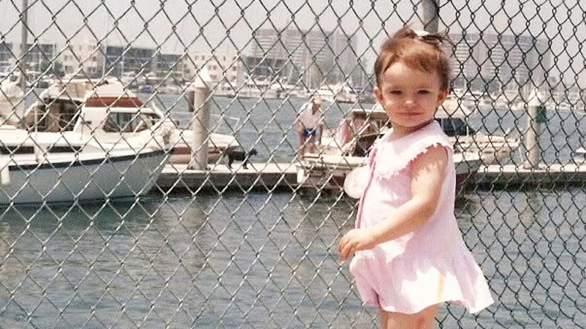 Caitlin O'Connor as a child wearing a pink dress.