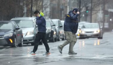 two men battling the high wind walking down a street