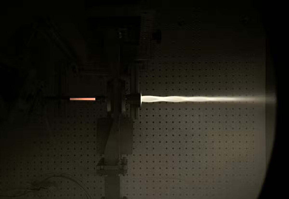 A flame shoots out of a thruster in a contained experiment