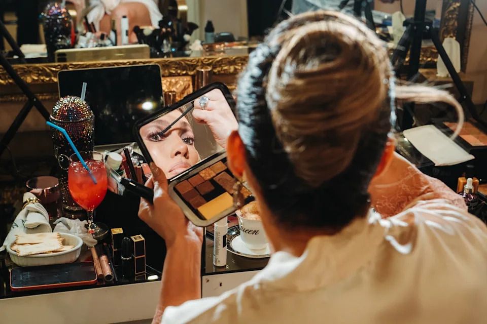 makeup application in a vibrant setting with various beauty products and a cocktail