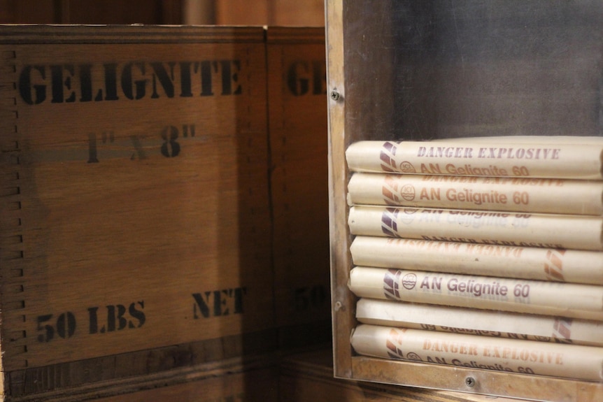 A dove-tailed wooden box reads 'Gelignite'. Next to it is a magazine of stacked gelignite packages. 