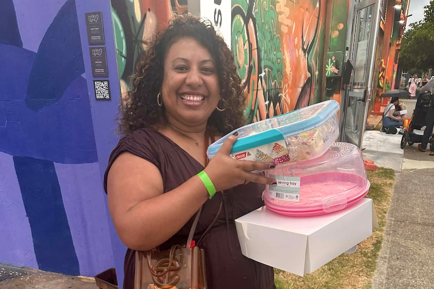 A woman smiling and holding a few tupperware cake containers