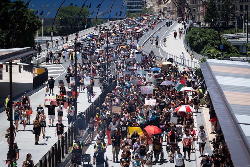 A view from above of a large crowd of people marching across Victoria Bridge in Brisbane.