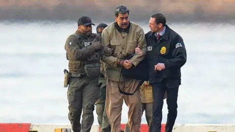 Getty Images Nicolás Maduro is seen in handcuffs after landing at a Manhattan helipad, escorted by heavily armed Federal agents as they make their way into an armored car en route to a Federal courthouse in Manhattan on January 5, 2026 in New York City. 