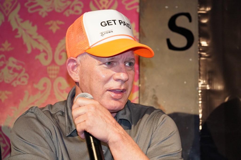 Former Met Lenny Dykstra speaks into a microphone, wearing a white and orange hat that says "GET PAID."