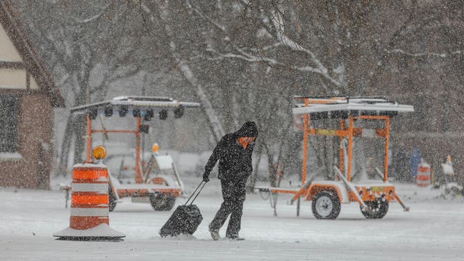 A pedestrians pulls a roller bag through the snow during a snowstorm in Chicago, Illinois, US, on Saturday, Nov. 29, 2025. Hundreds of flights have been canceled in and around Chicago and roads are becoming treacherous as one of the busiest travel weekends of the year collides with a major storm bringing wintery conditions throughout the US Midwest Saturday.