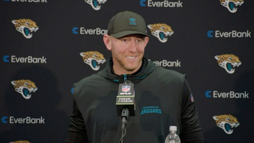 Jaguars head coach Liam Coen smiling while speaking into a microphone.