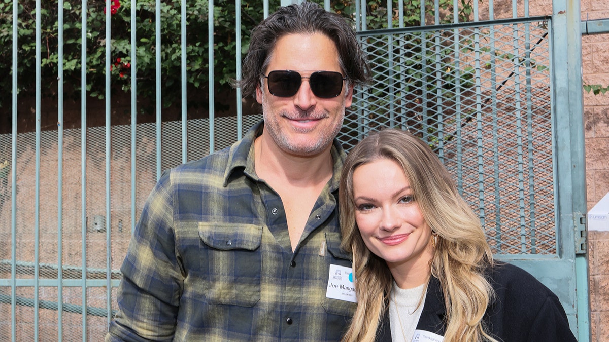 Joe Manganielle wearing a plaid shirt embracing Caitlin O'Connor in a black blazer and white shirt.