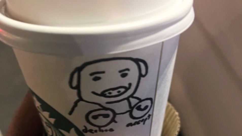 A Starbucks coffee cup with a hand-drawn illustration of a pig on it.