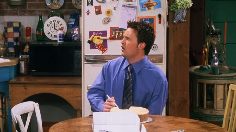 Chandler Bing sits at the kitchen table looking surprised in 