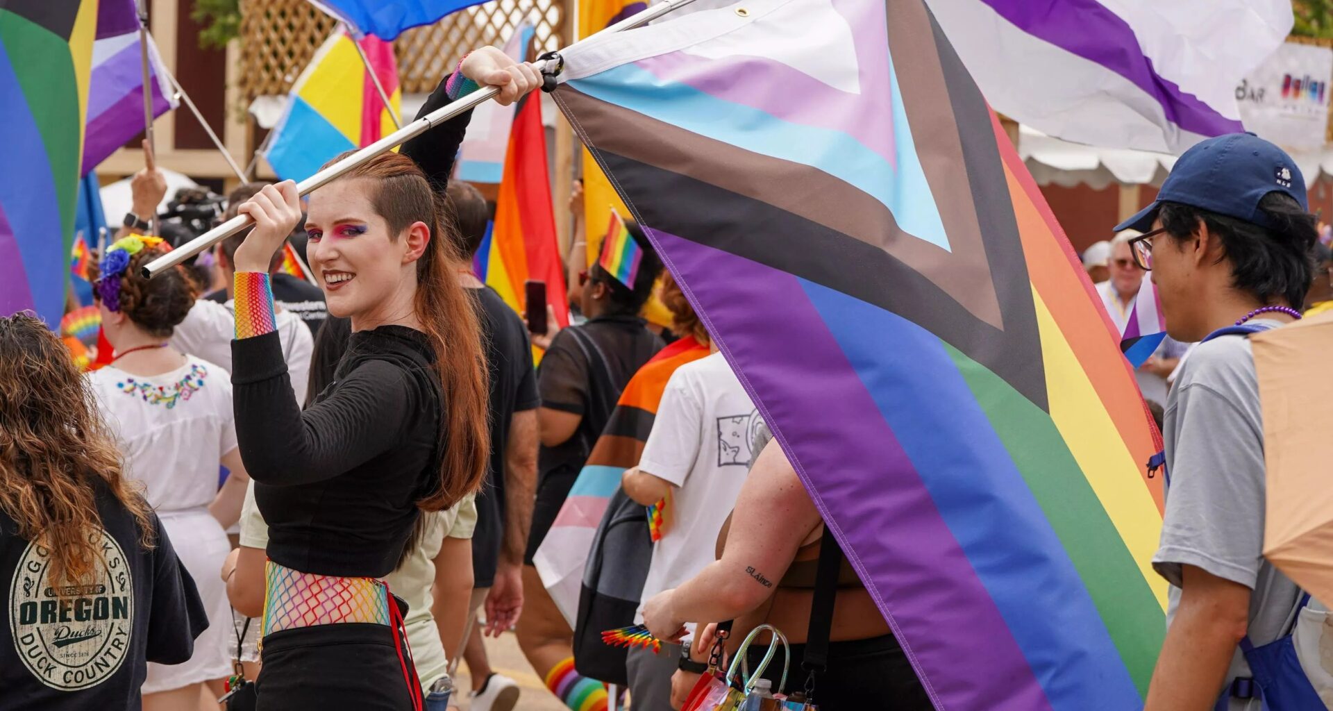 Person carrying the LGBTQ+ Pride flag during a Pride Parade in Dallas