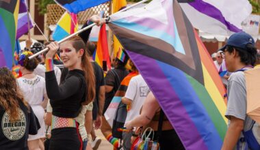 Person carrying the LGBTQ+ Pride flag during a Pride Parade in Dallas