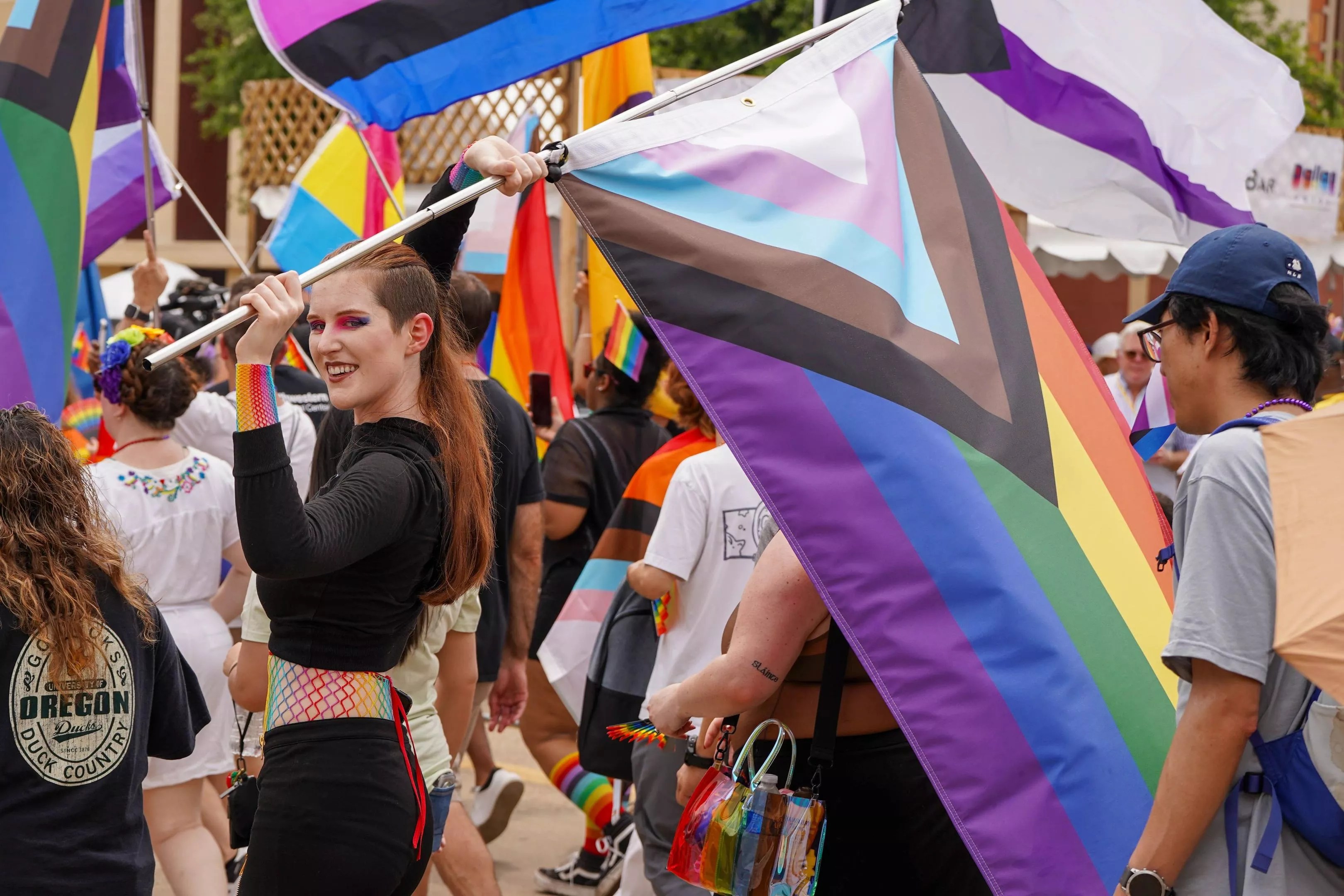 Person carrying the LGBTQ+ Pride flag during a Pride Parade in Dallas