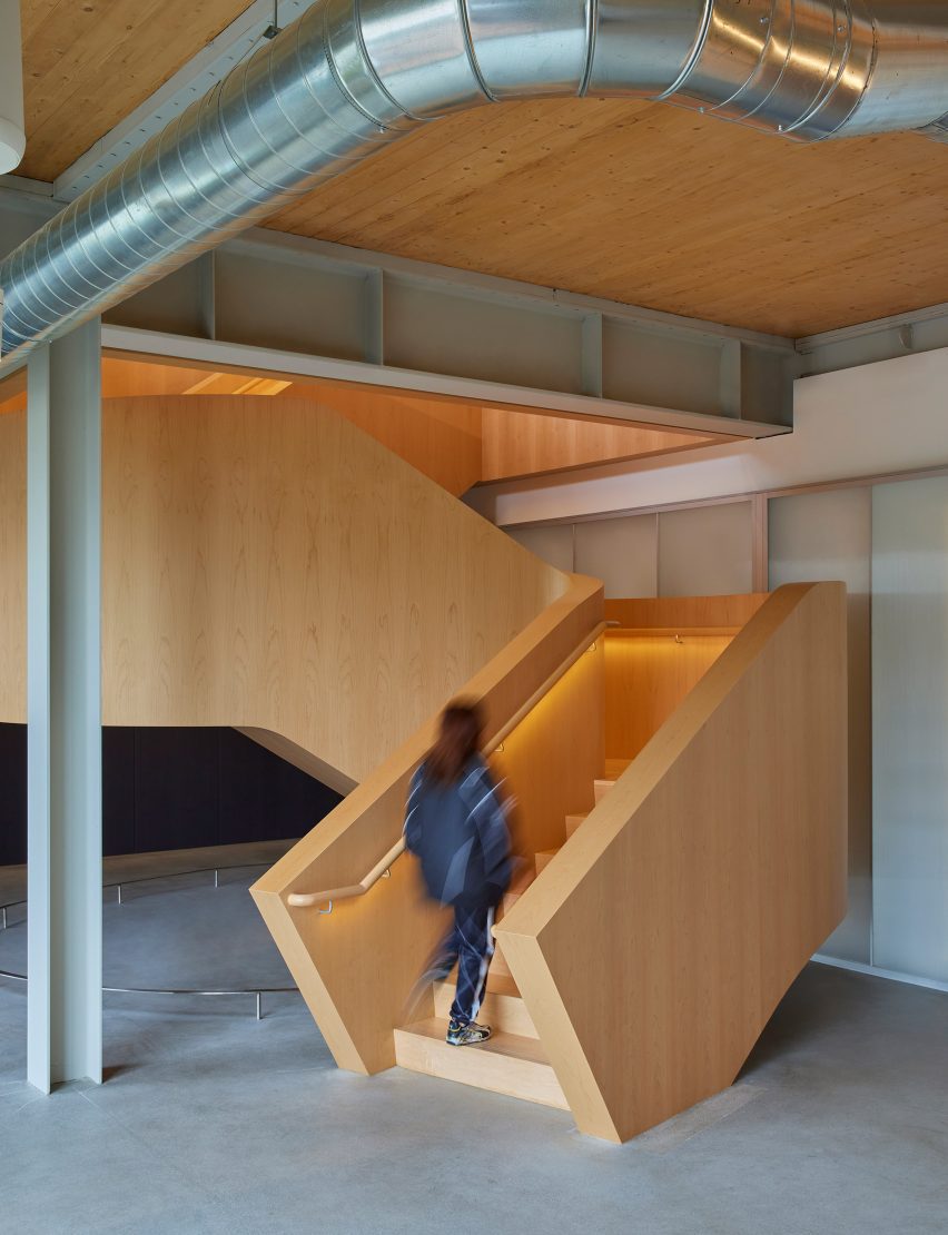 A wooden staircase within a minimalist concrete and glass space