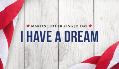 Martin Luther King Jr. Day "I have a dream" text in blue against a wood grain background and American Flag at the edges.