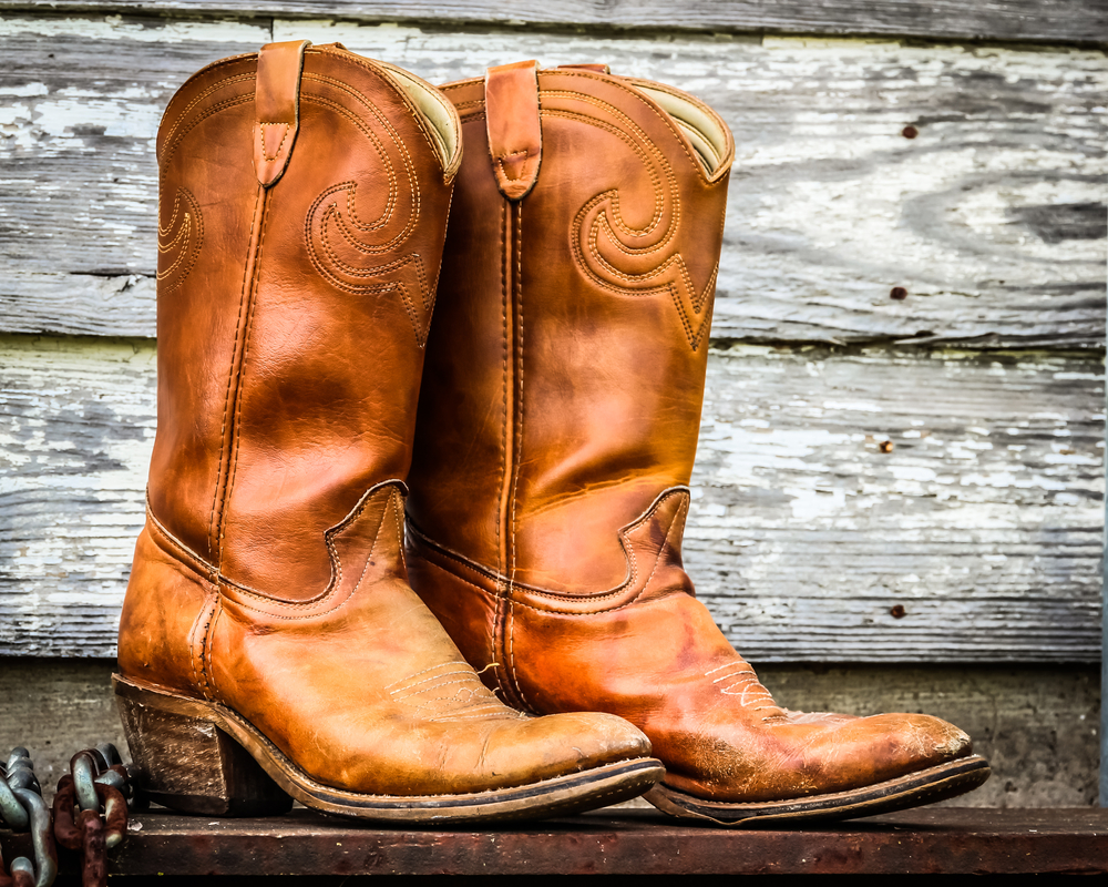 cowboy boots in front of a wood background.