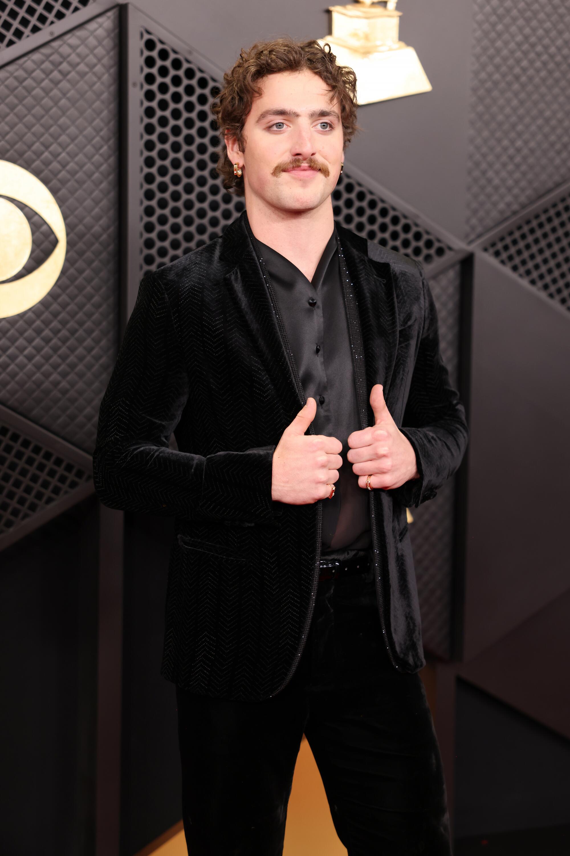 Benson Boone, wearing a black velvet tux, poses on the red carpet. 