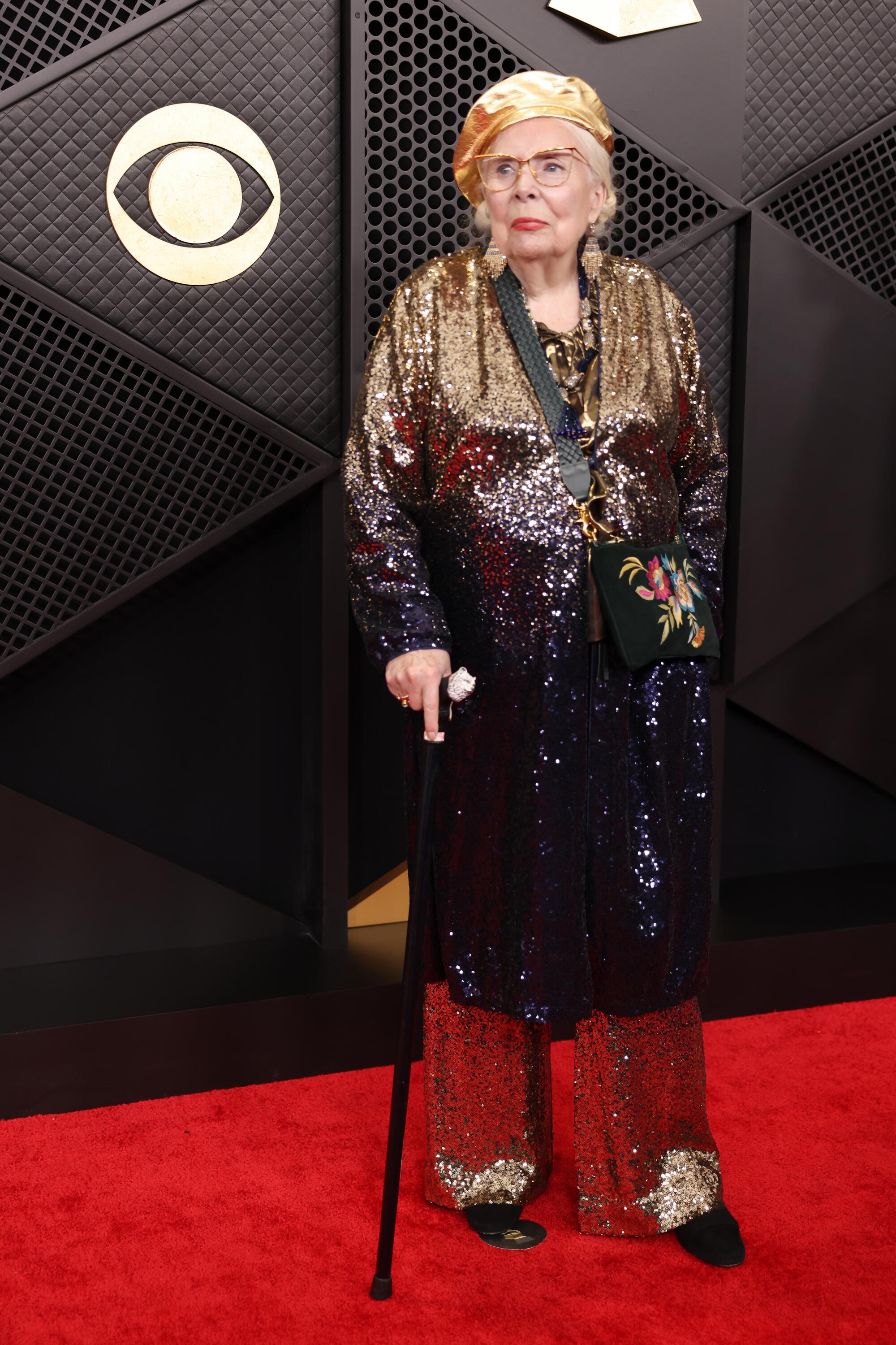 Joni Mitchell walks with a cane on the red carpet. 