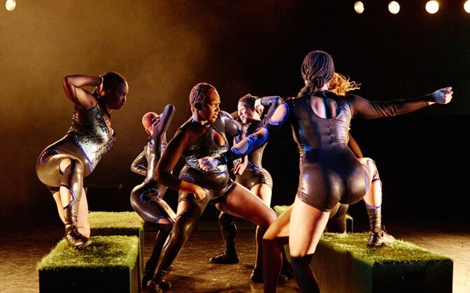 A group of Black dancers wearing black outfits perform on stage.