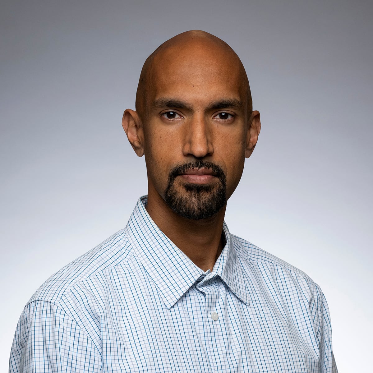 A headshot of Sachin, in front of a grey background 