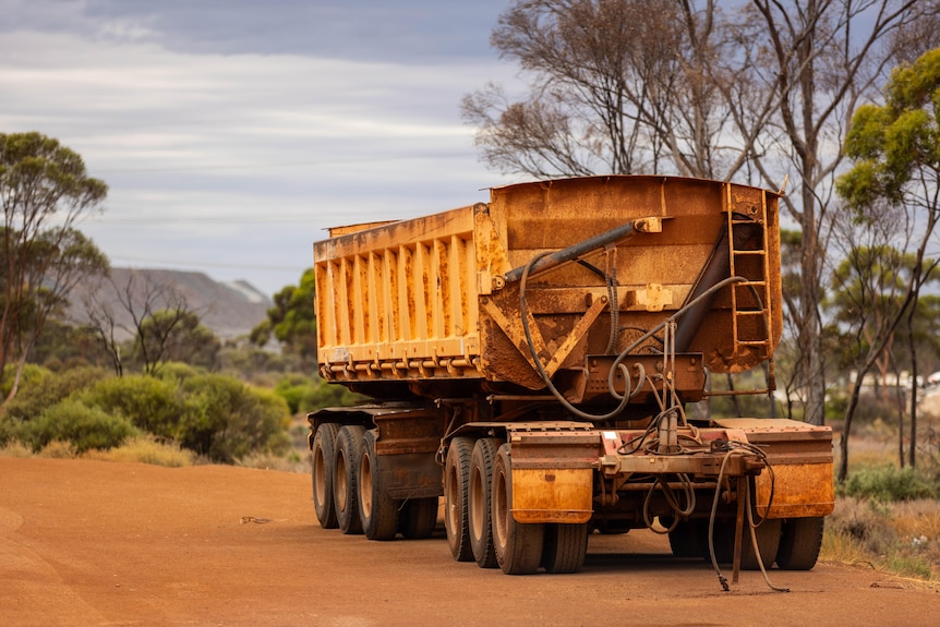 A trailer for a road train parked on a dirt road.