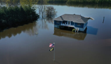 The aerial view shows a modest house and the American flag out front partially underwater.