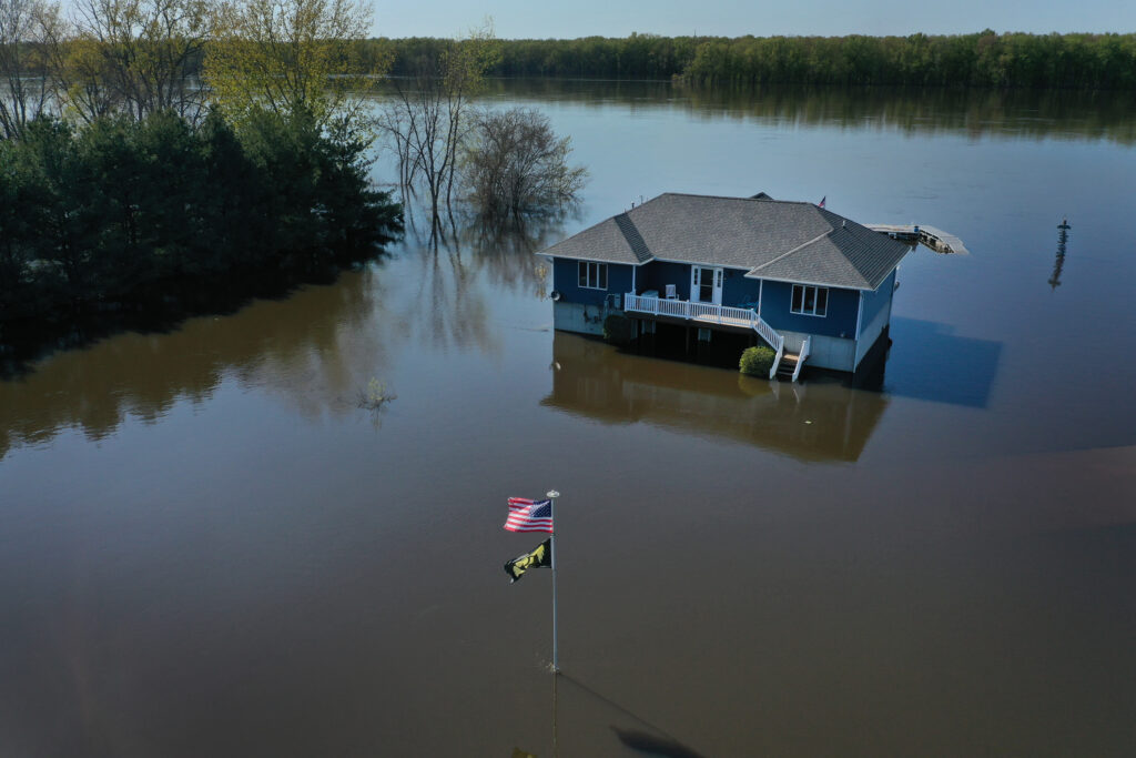 The aerial view shows a modest house and the American flag out front partially underwater.