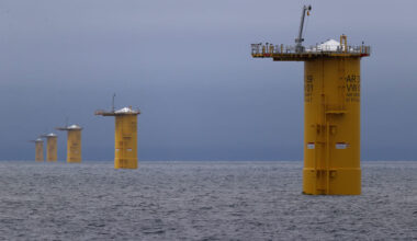 Image of a series of metal cylinders rising vertically from the ocean.