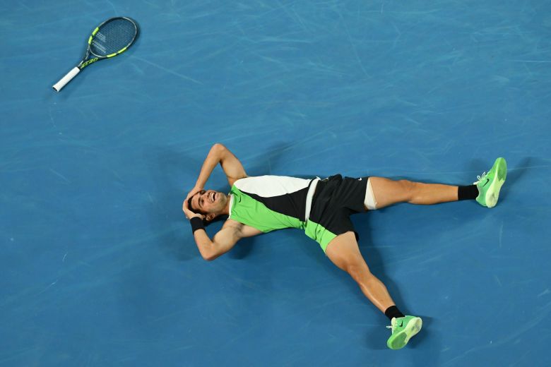 Alcaraz falls to the floor in celebration after sealing the win.