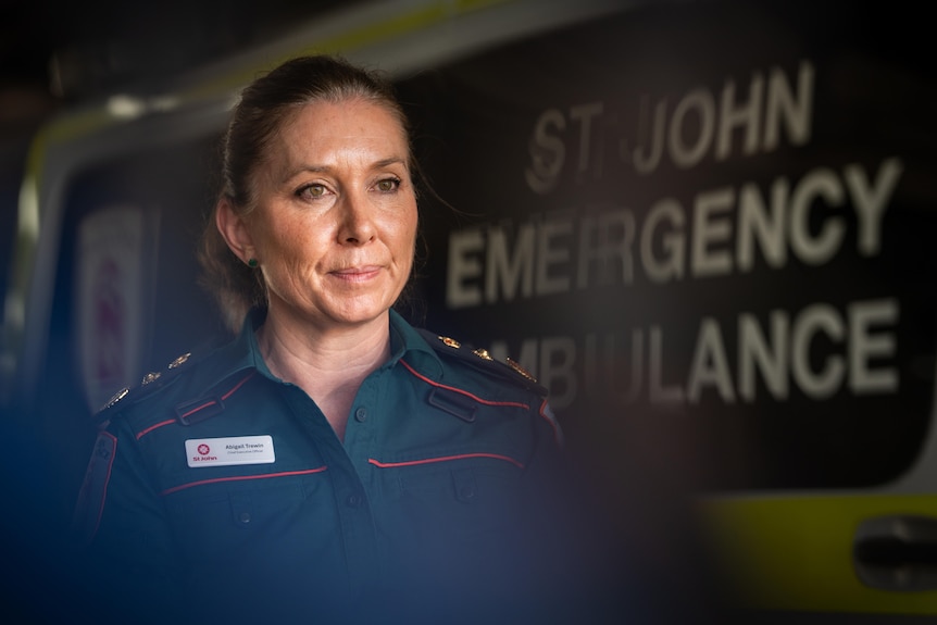 Woman in paramedic uniform stands in front of ambulance