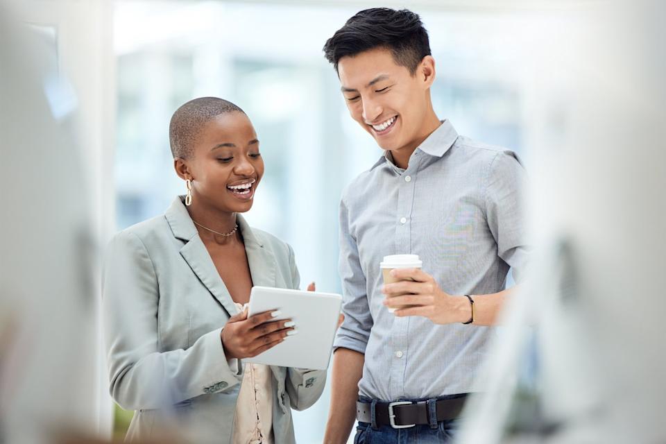 Two people smiling while looking at tablet.