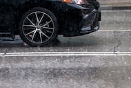 A car drives along Commerce Street as heavy rain falls in downtown Dallas, Wednesday, April...