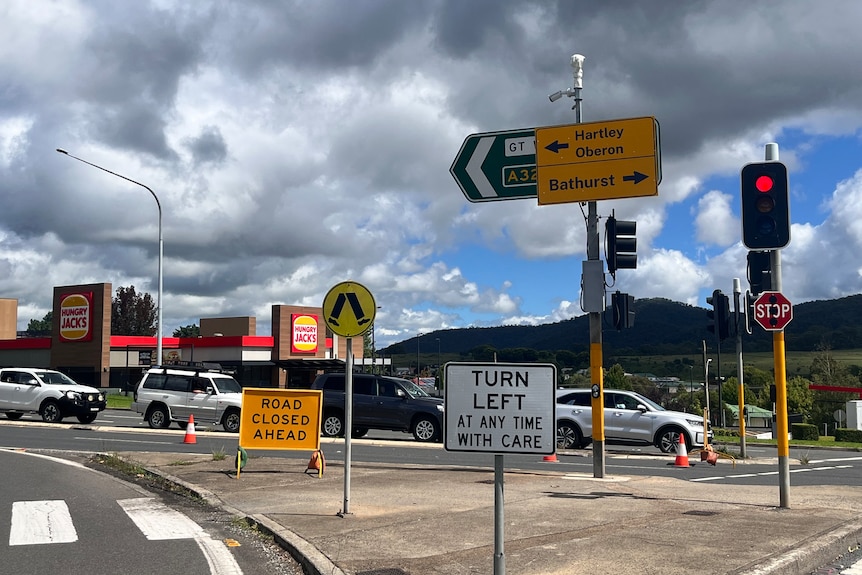 Picture of road closed and detour signs, with cars lined up at traffic lights