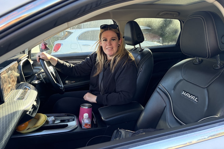 Woman behind steering wheel looking out passenger window
