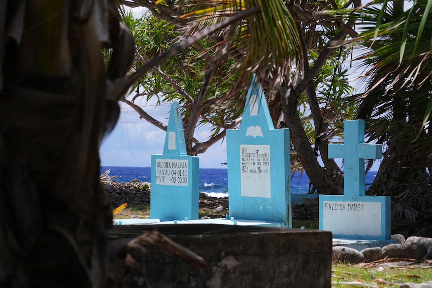 A photo of blue tombstones with a backdrop of the sea.
