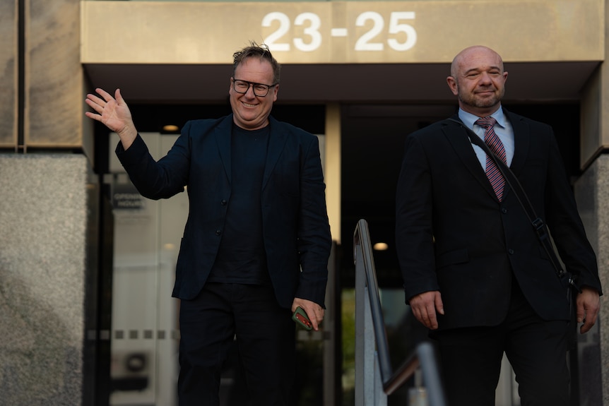 Two men leave a court building, smiling