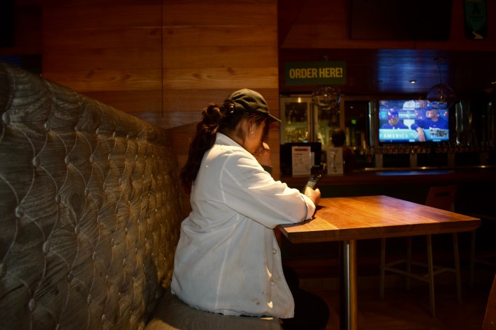 a young woman sits at a restaurant booth