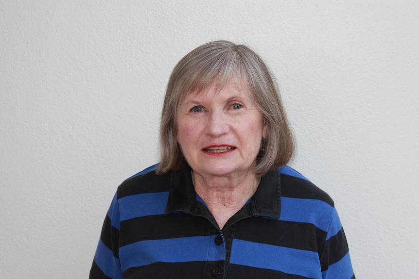 A woman in a black and gray shirt smiles at the camera.